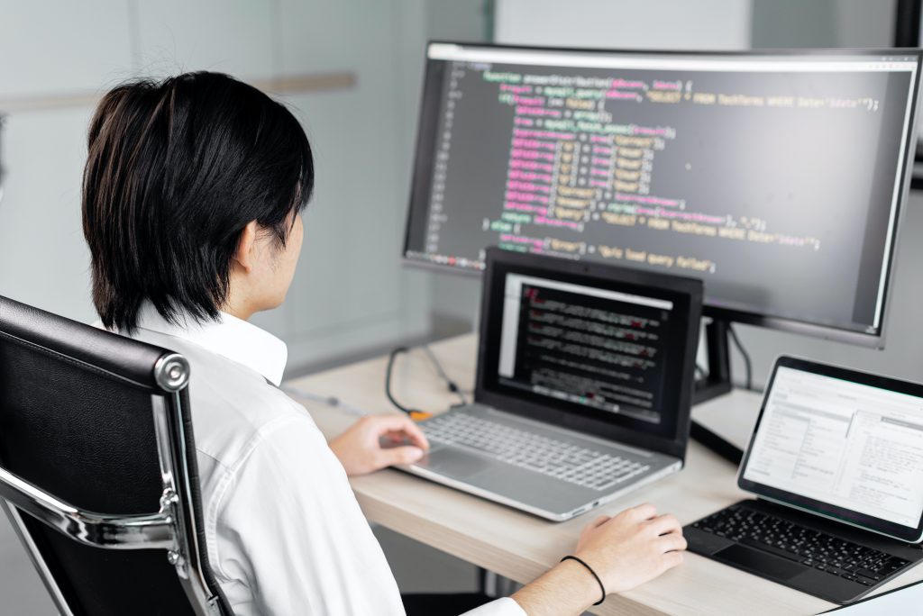 A person sitting in front of three computers