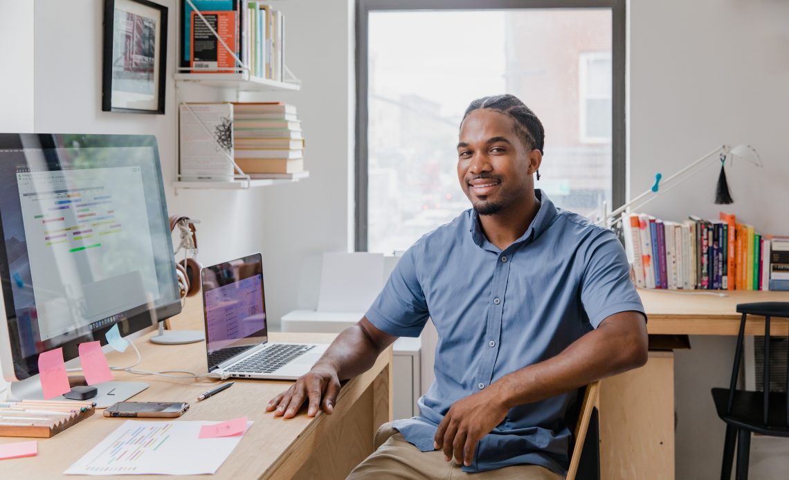 the man in the blue shirt is sitting across from the computer